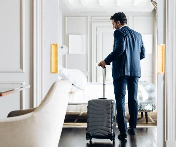Businessman with wheeled luggage in suite