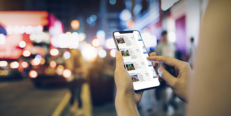 Woman using mobile phone for navigating direction in busy city street